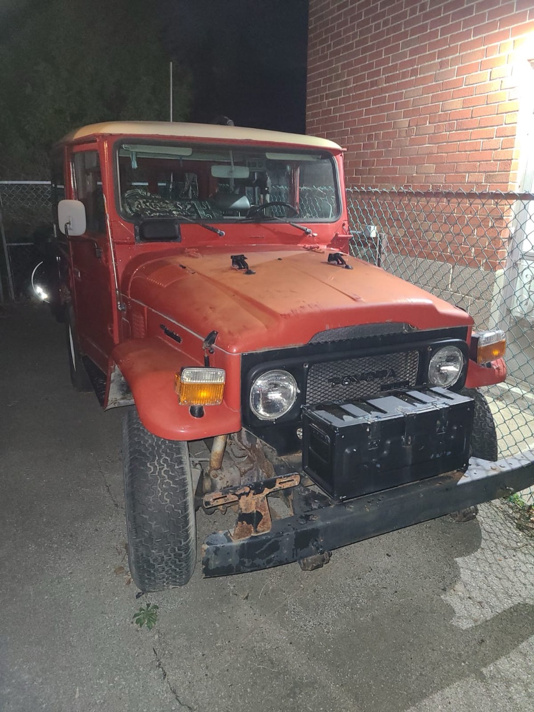 BJ40 Land Cruiser parked at night beside a brick wall