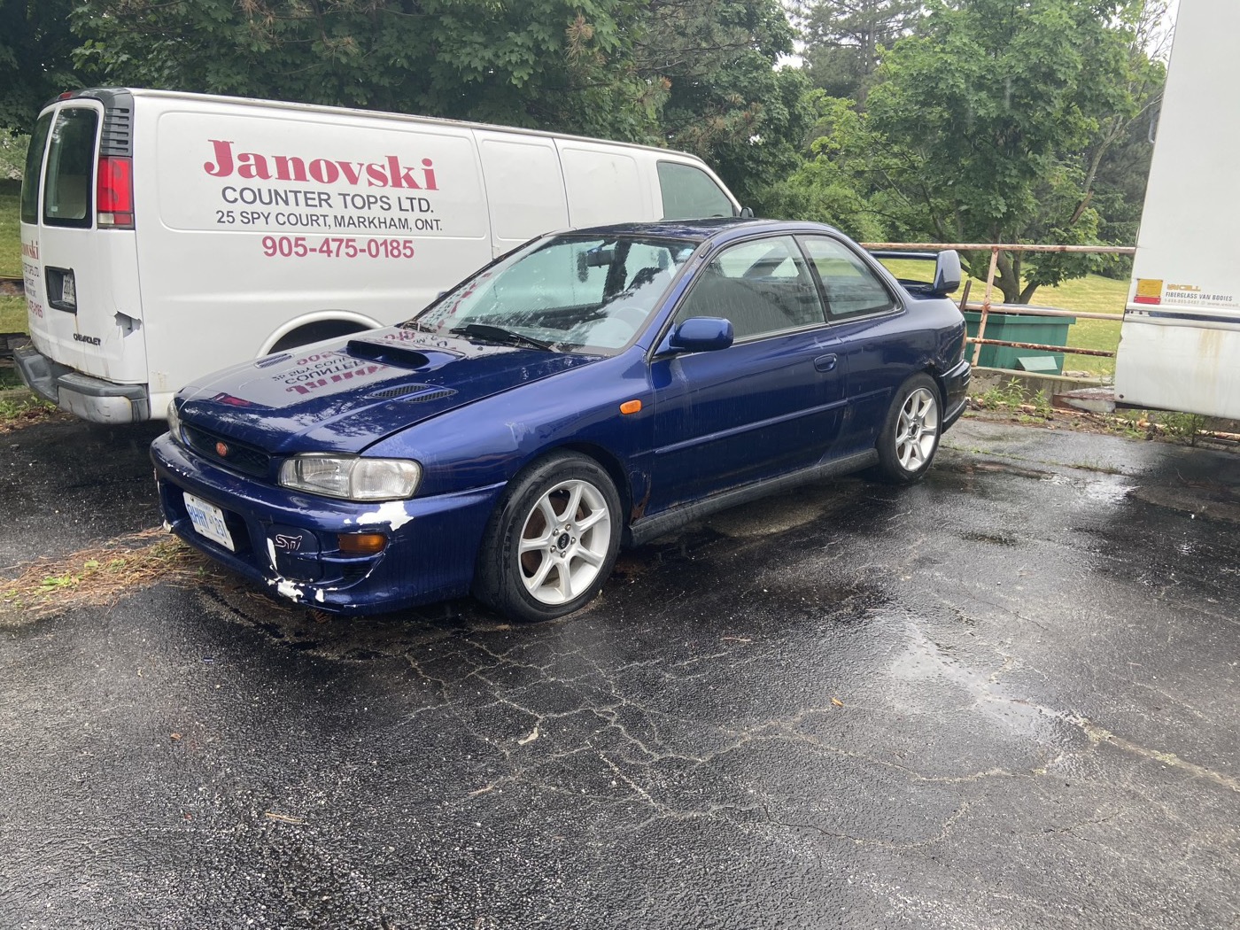 Blue GC8 Impreza sedan parts car in the rain