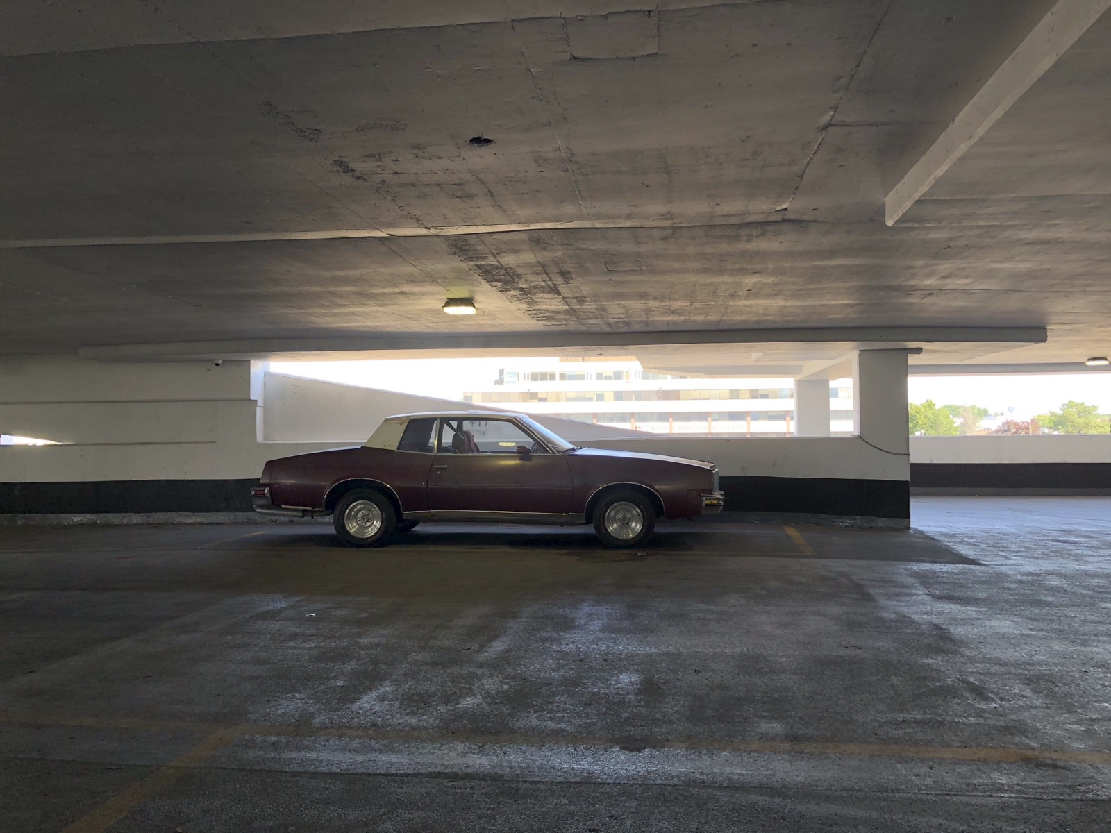 1978 Pontiac Grand Prix parked alone on the top deck of a parking garage at golden hour