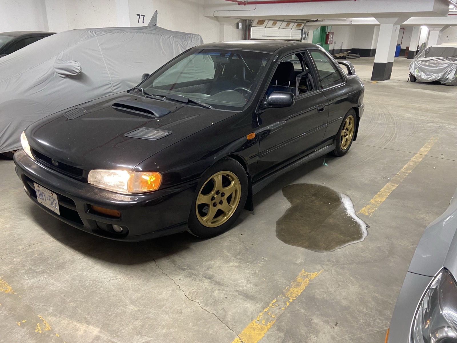 Black 2000 Subaru Impreza 2.5RS coupe with gold wheels in an underground garage