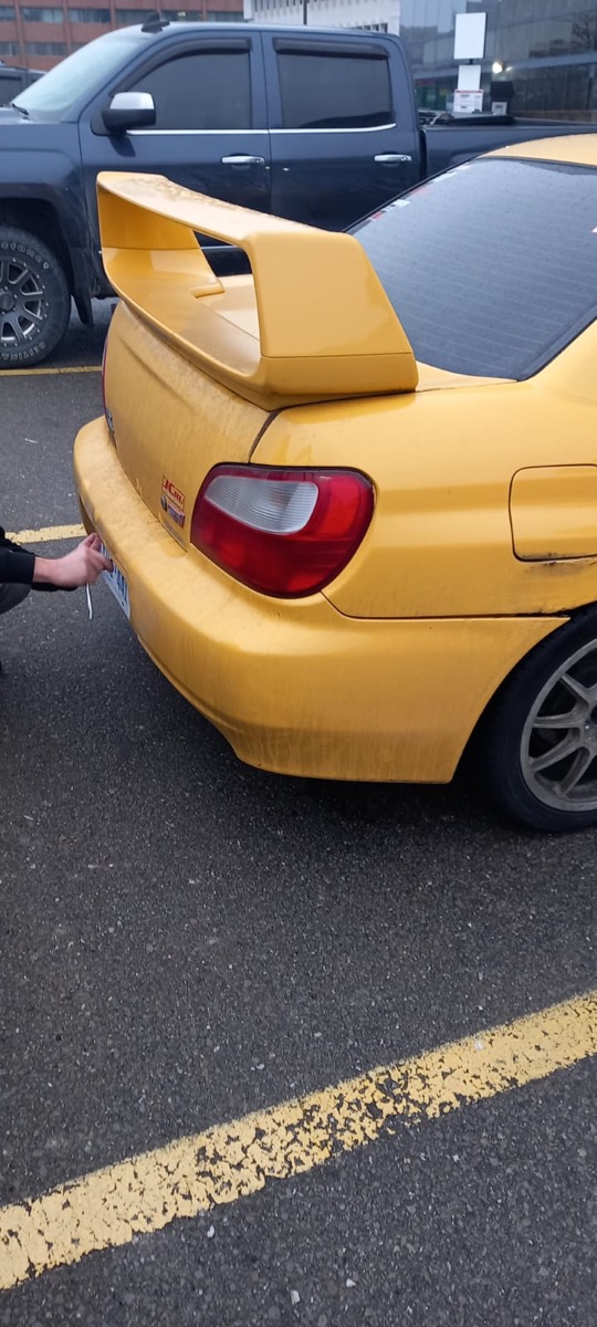 Rear wing and tail light of a yellow Subaru WRX